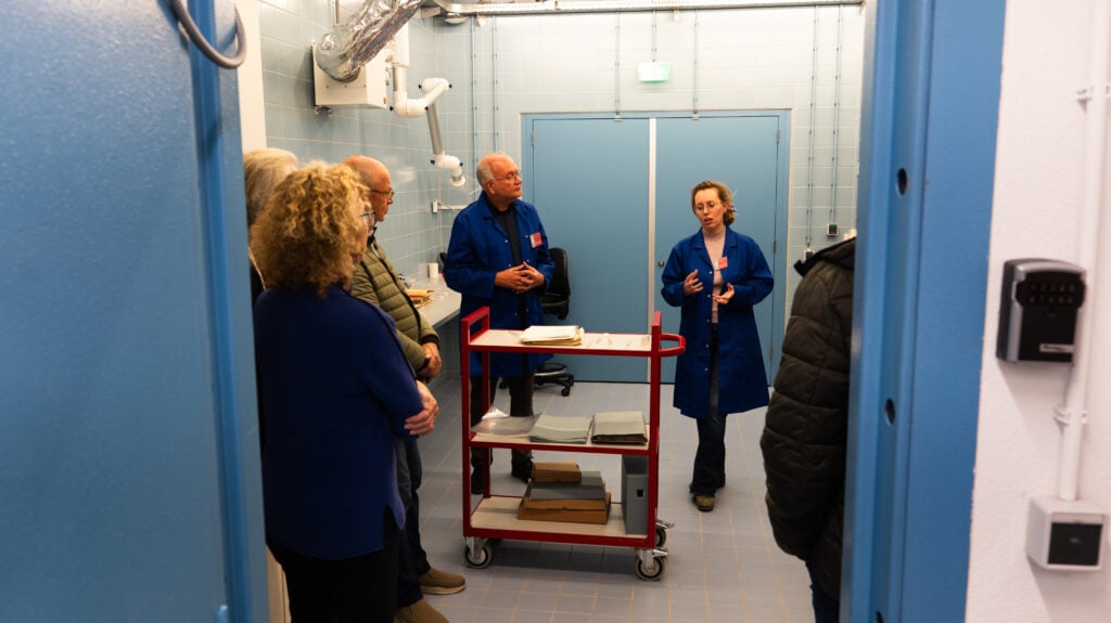 Groep mensen luisteren naar twee medewerkers van het Westfries Archief