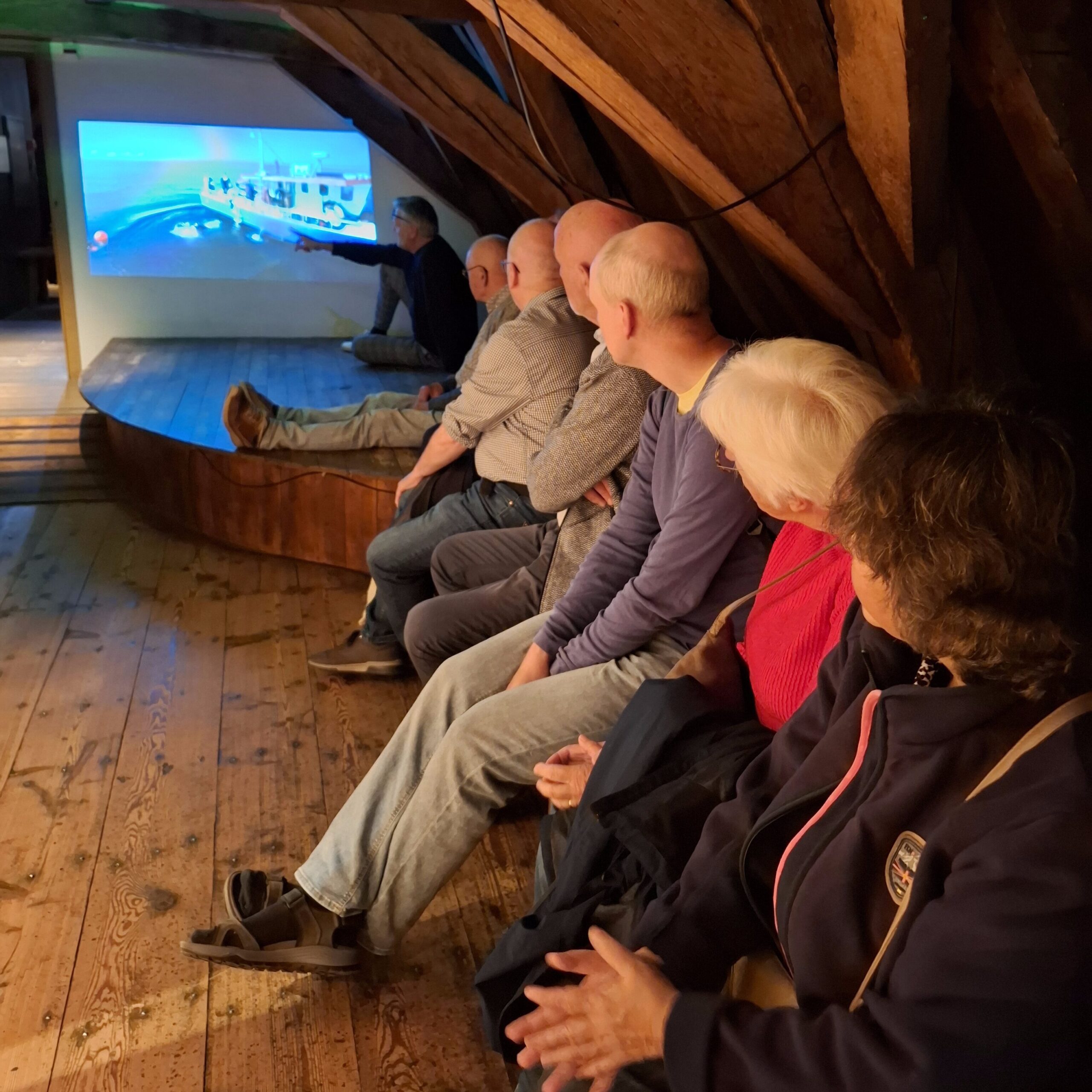 Vrijwilligers luisteren aandachtig naar een gids in de Tentoonstelling Huis te Warmelo
