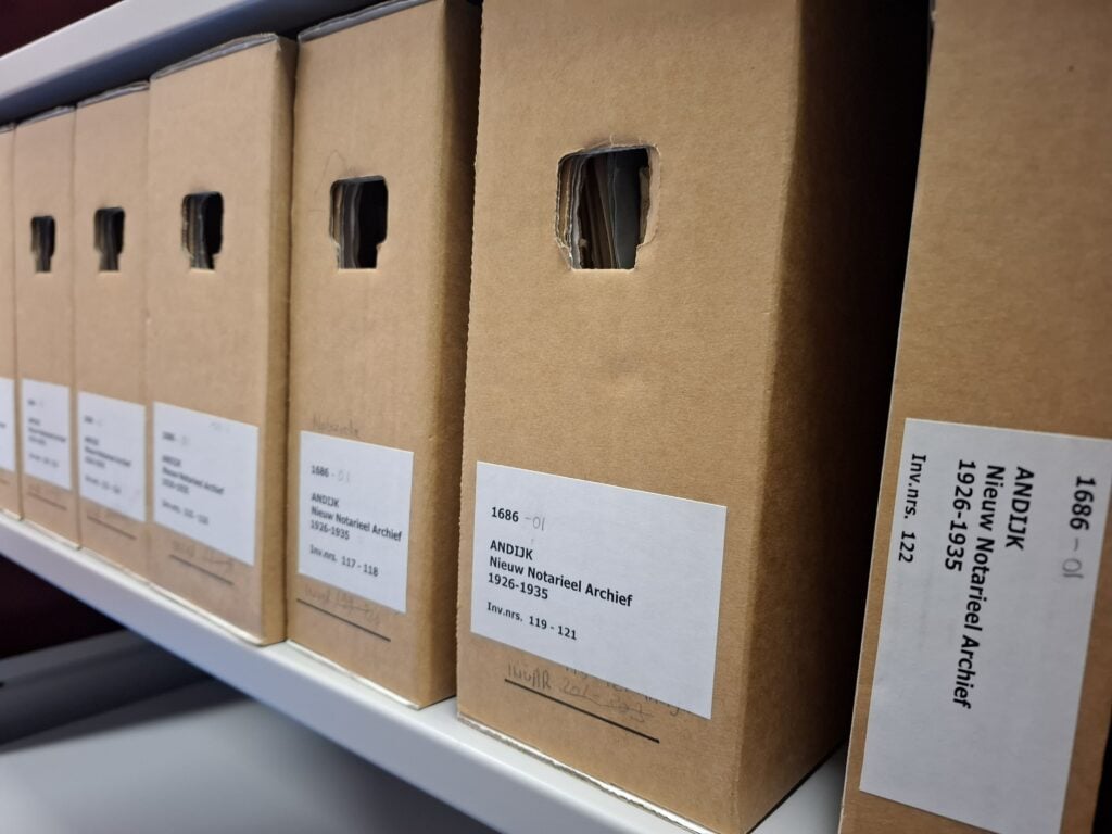 Rii met dozen geplaatst in een archiefkast. Op het etiket staat Nieuw Notarieel Archief Andijk