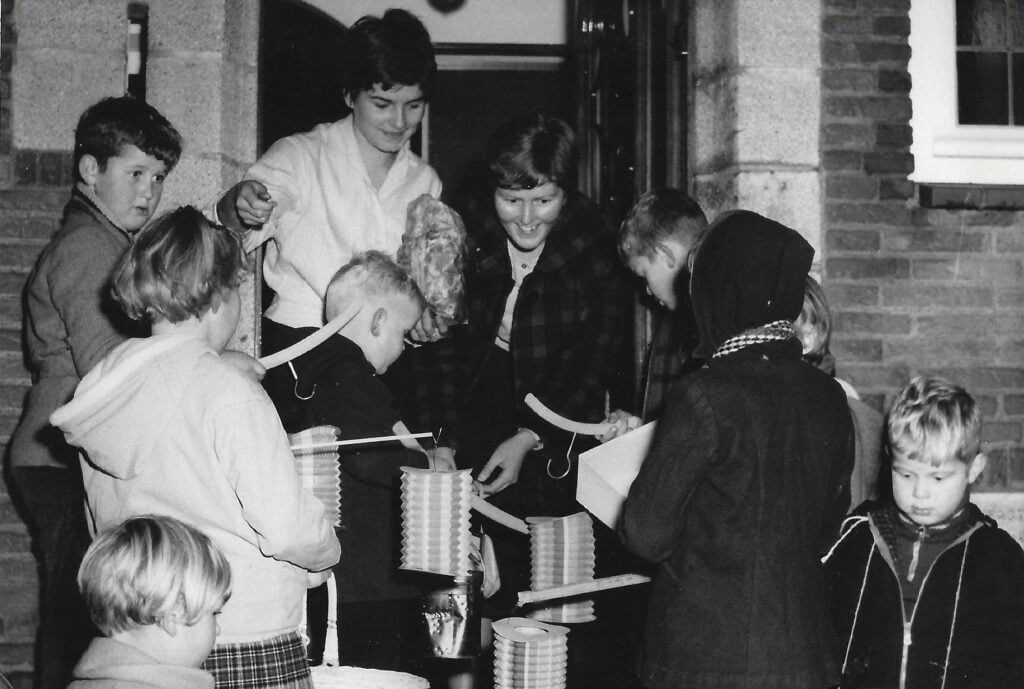 Sint-maartenviering in Hoorn. Kinderen staan met lampions voor een geopende deur