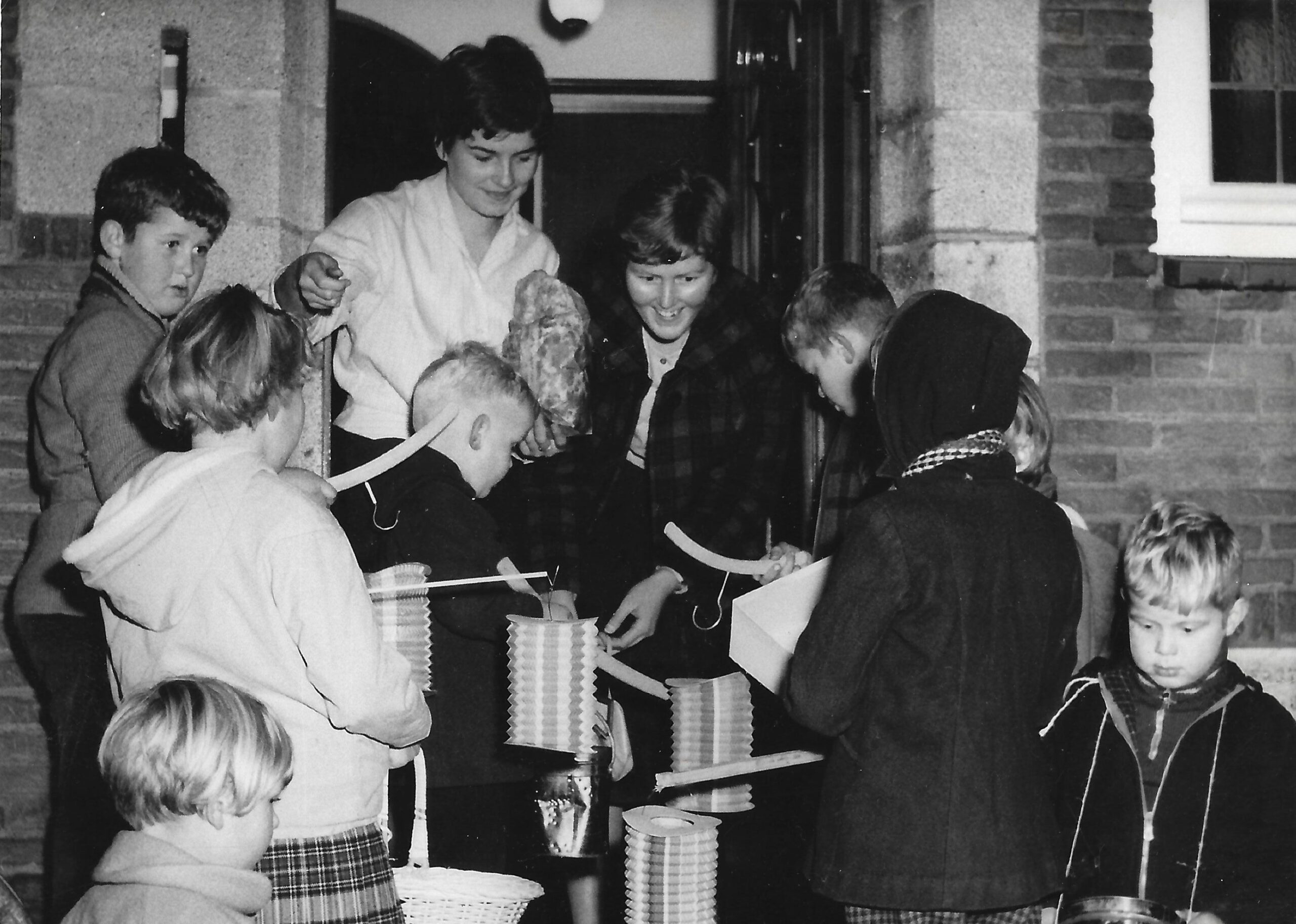 Sint-maartenviering in Hoorn. Kinderen staan met lampions voor een geopende deur