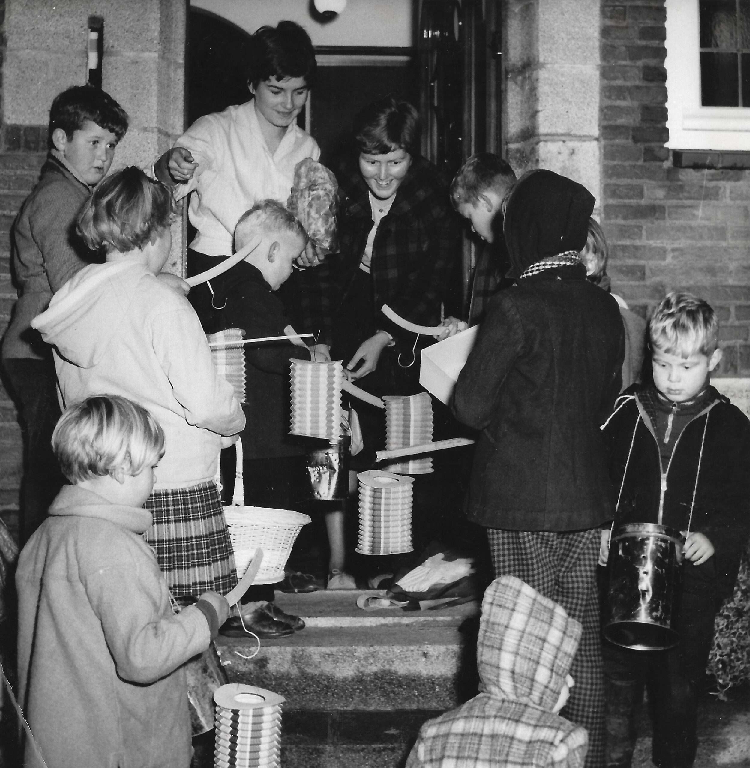 Sint-maartenviering in Hoorn. Kinderen staan met lampions voor een geopende deur