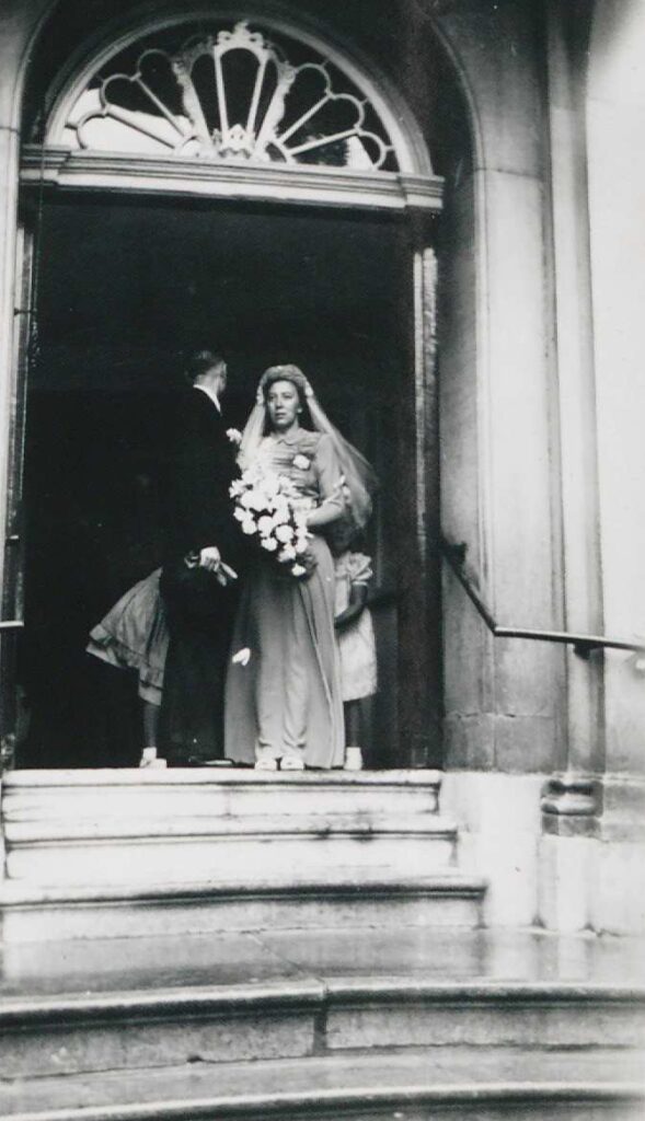 Foto van bruidspaar voor de deur van het Stadhuis in Enkhuizen, circa 1930-1950.
