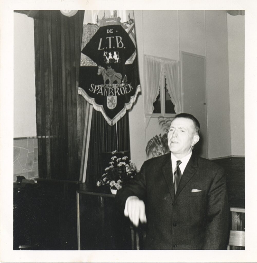 Lid van de L.T.B. afdeling Spanbroek poseert voor de clubvlag